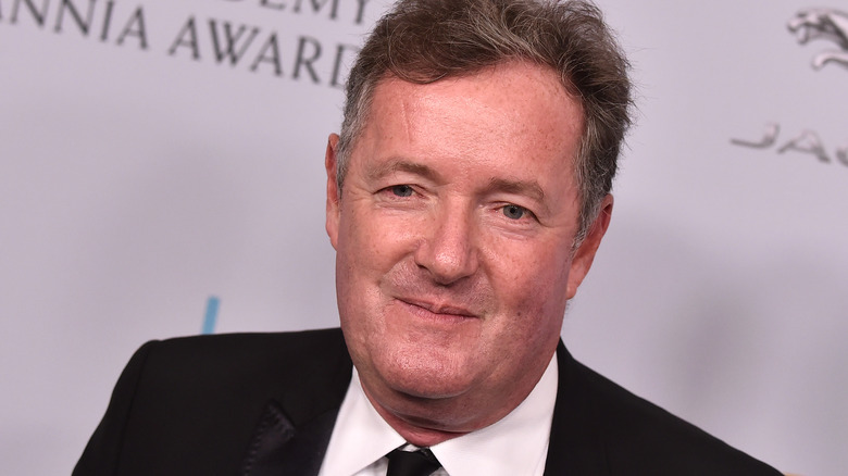 Piers Morgan poses in a black suit and white shirt