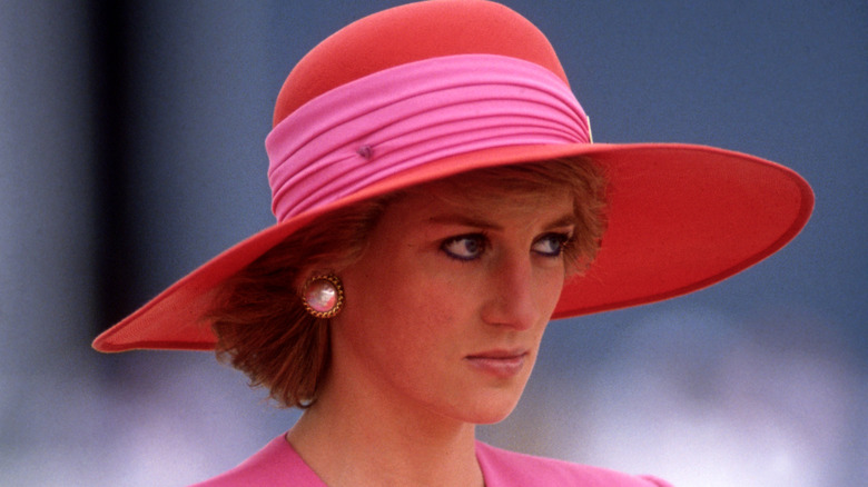 Princess Diana at an event, looking solemn, pink and red hat