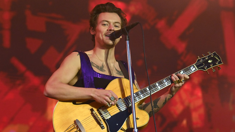 Harry Styles on stage with a guitar