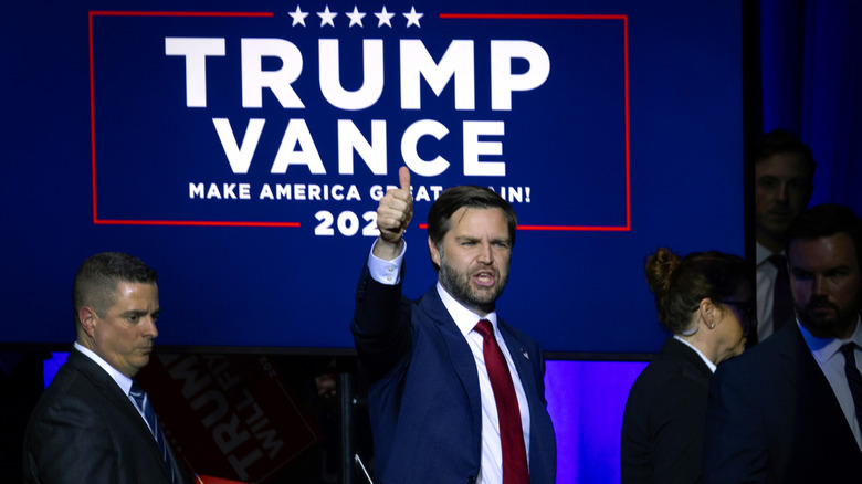 JD Vance thumbs up in front of Trump/Vance sign