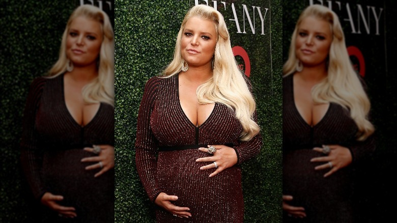 Jessica Simpson cradling baby bump, posing outdoors