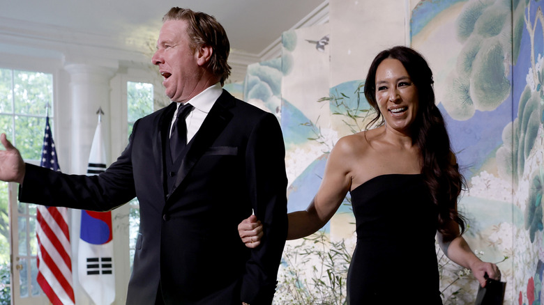 Chip Gaines waving as Joanna Gaines pulls him away