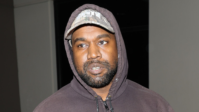 Kanye West wearing hoodie over cap