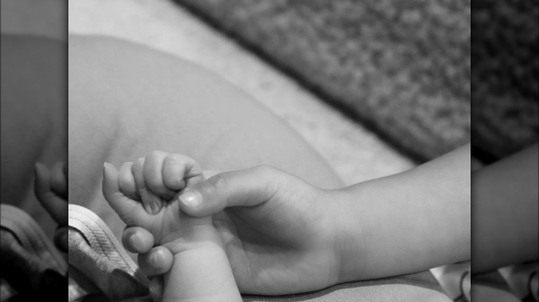 Stormi Webster holding hands with her baby brother