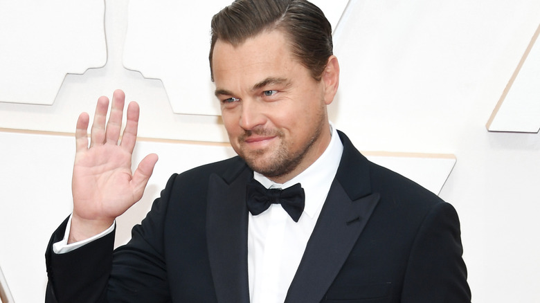 Leonardo DiCaprio waves while bowing his head