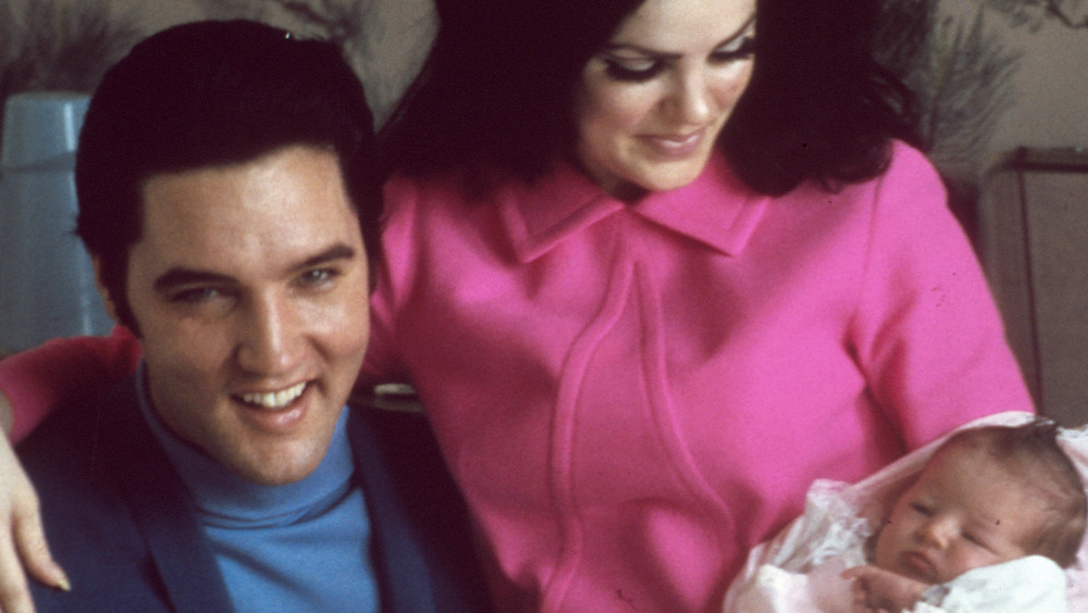 Elvis and Priscilla Presley holding baby Lisa Marie