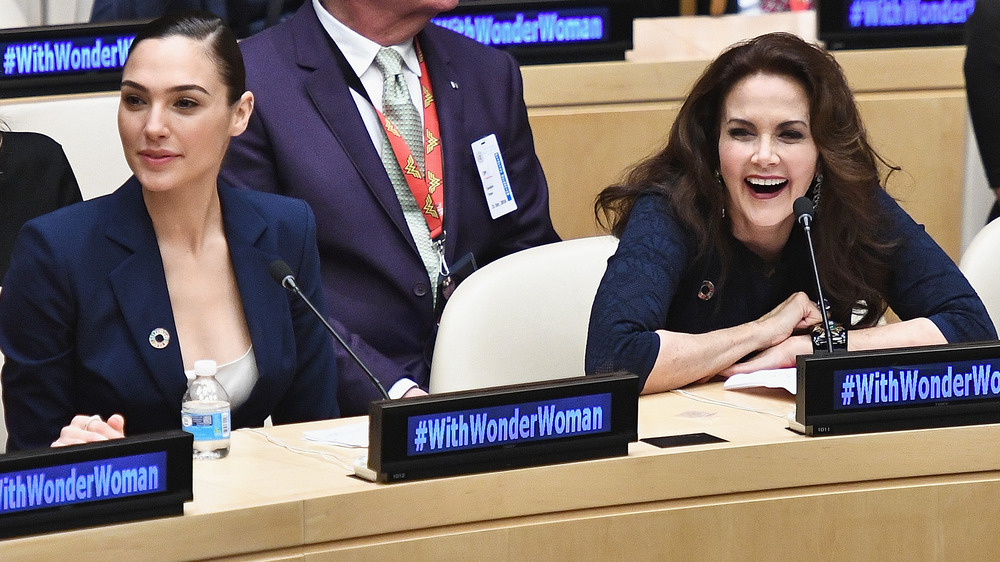 Gal Gadot and Lynda Carter sit side-by-side at an event titled "With Wonder Woman"