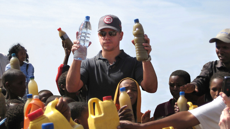 Matt Damon holds a bottle of dirty water in Africa