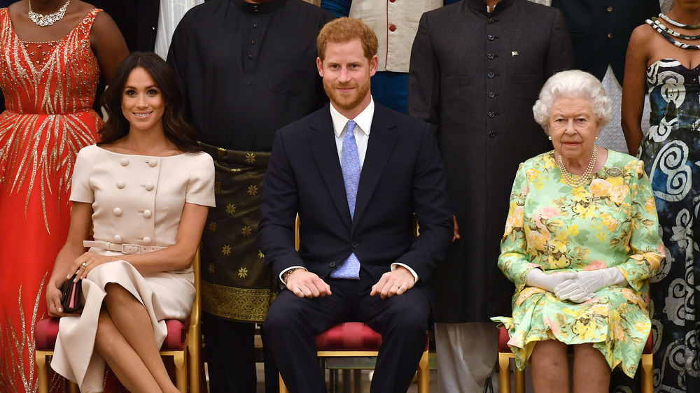 Queen Elizabeth, Prince Harry, and Meghan Markle, all seated