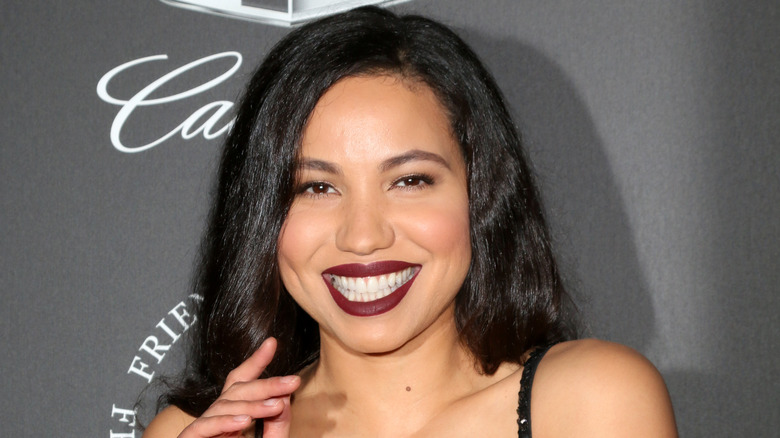 Jurnee Smollett smiling with hand raised