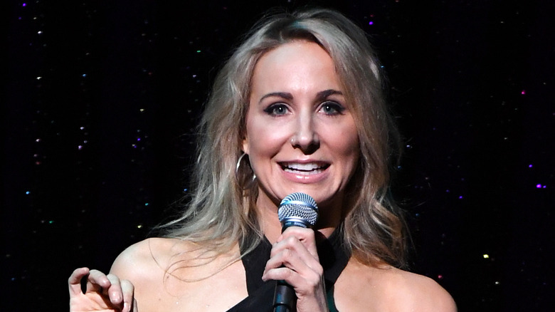 Nikki Glaser performs onstage with a microphone