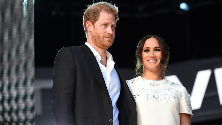 Prince Harry and Meghan Markle smiling on stage