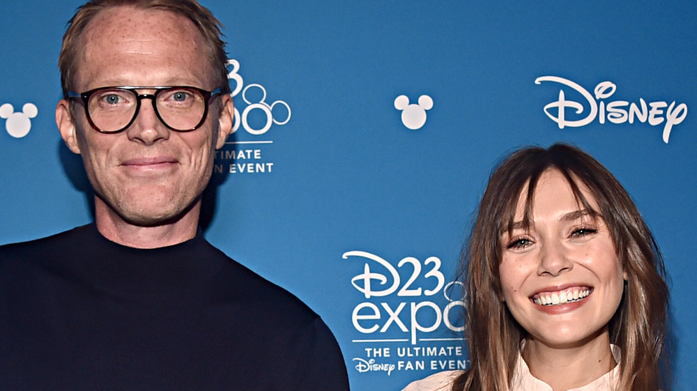 Paul Bettany and Elizabeth Olsen smiling with Olsen's hand on Bettany's arm