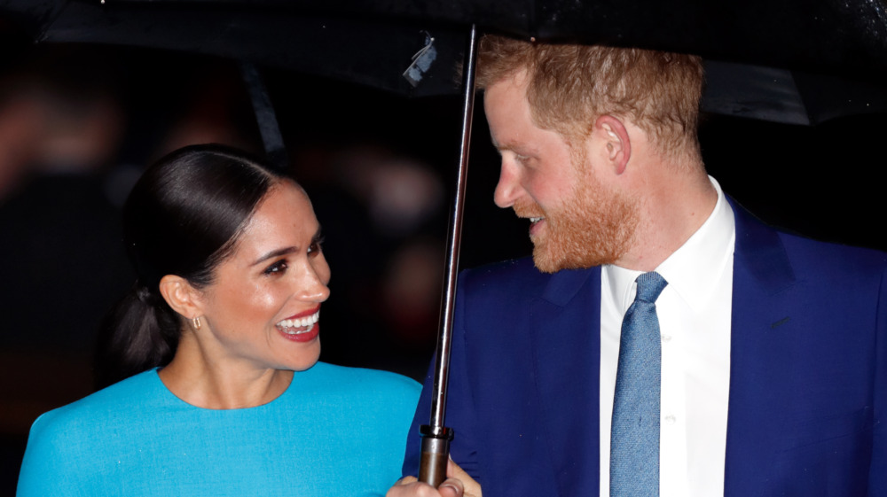 Meghan Markle and Prince Harry laughing beneath umbrella