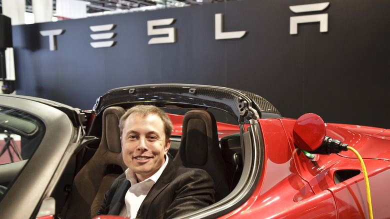 Elon Musk sitting in a Tesla