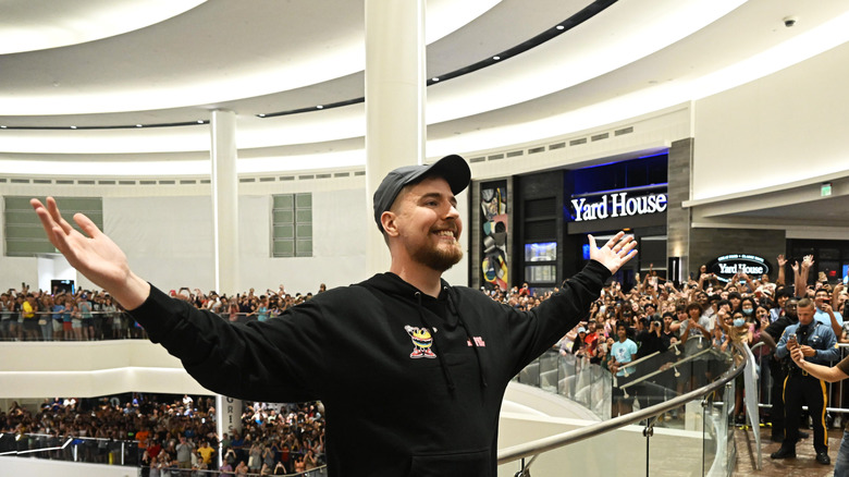 MrBeast standing in front of a crowd with his arms lifted.