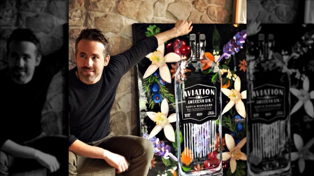 Ryan Reynolds posing with a painting of an Aviation gin bottle