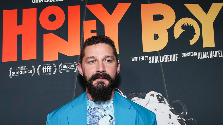 Shia LaBeouf in front of Honey Boy poster