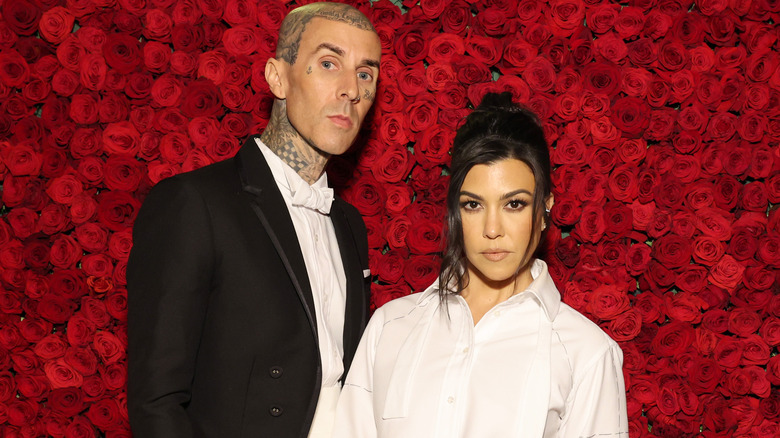 Travis Barker and Kourtney Kardashian pose in front of rose wall