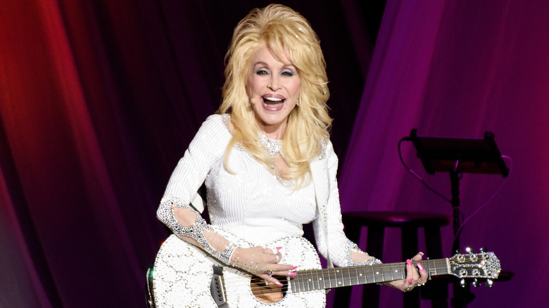 Dolly Parton smiling with her guitar