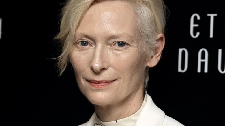 Tilda Swinton standing before black background