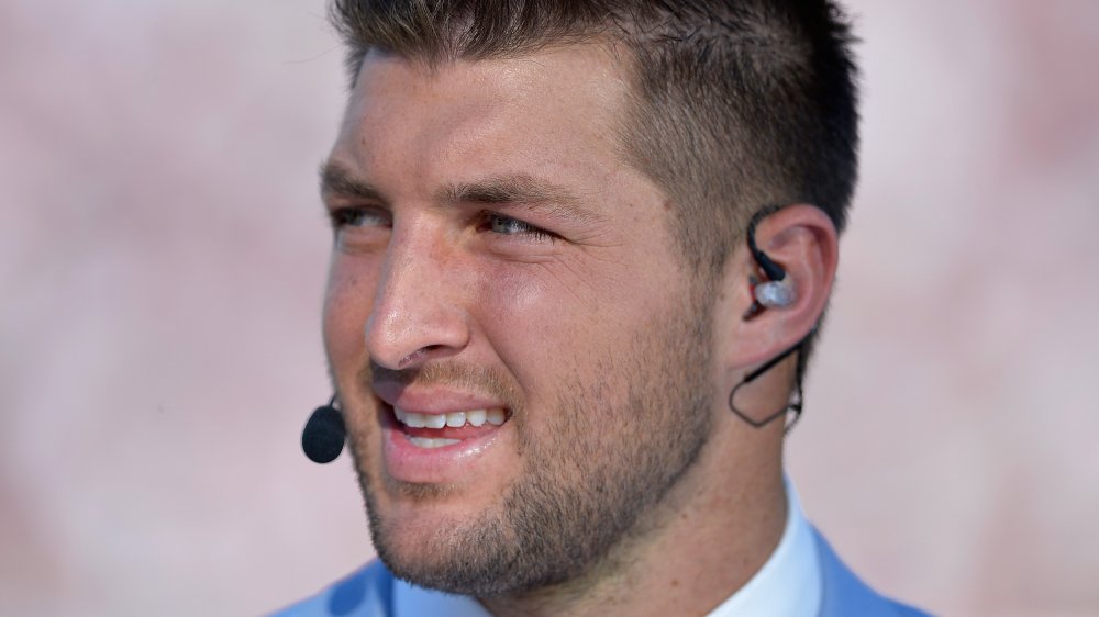 Tim Tebow speaking into a mic, looking off to the side