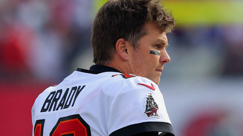 Tom Brady on the field with helmet off