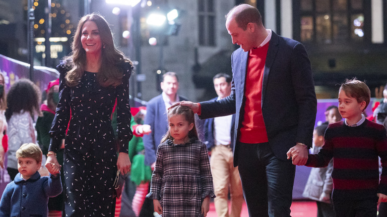 Prince William and Kate Middleton holding hands and laughing with their children