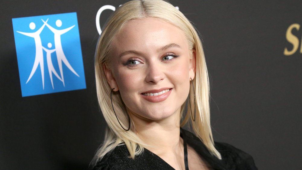 Zara Larsson smiling, with straight hair and black hoops