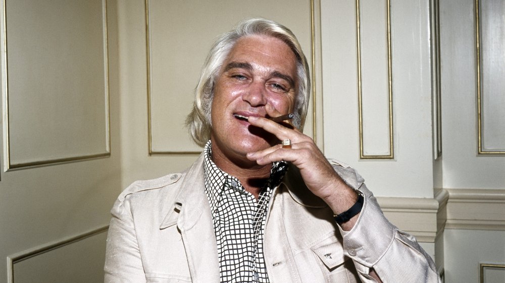 Charlie Rich sitting back, smiling, and smoking