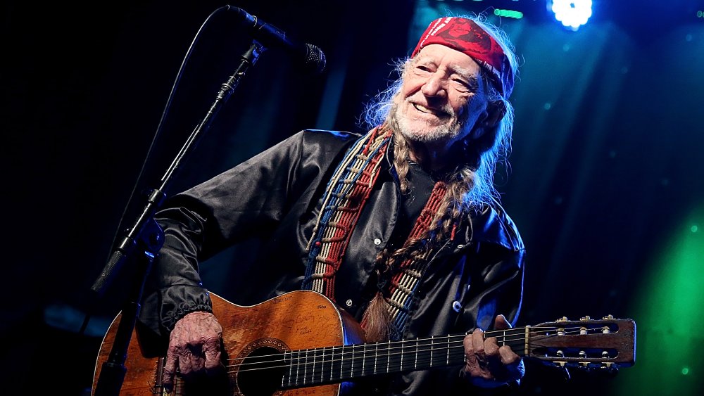 Willie Nelson smiling while playing guitar