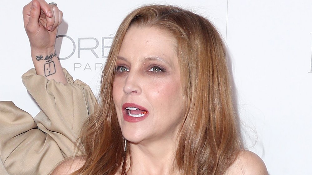 Lisa Marie Presley poses on the red carpet while speaking to her daughter, Riley Keough