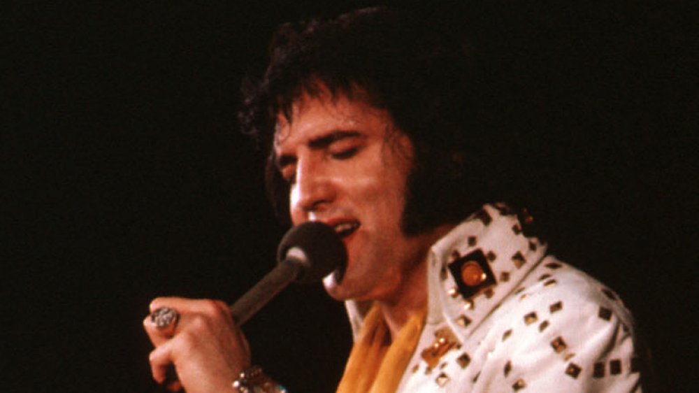 Elvis Presley performs in 1974 wearing a white jumpsuit