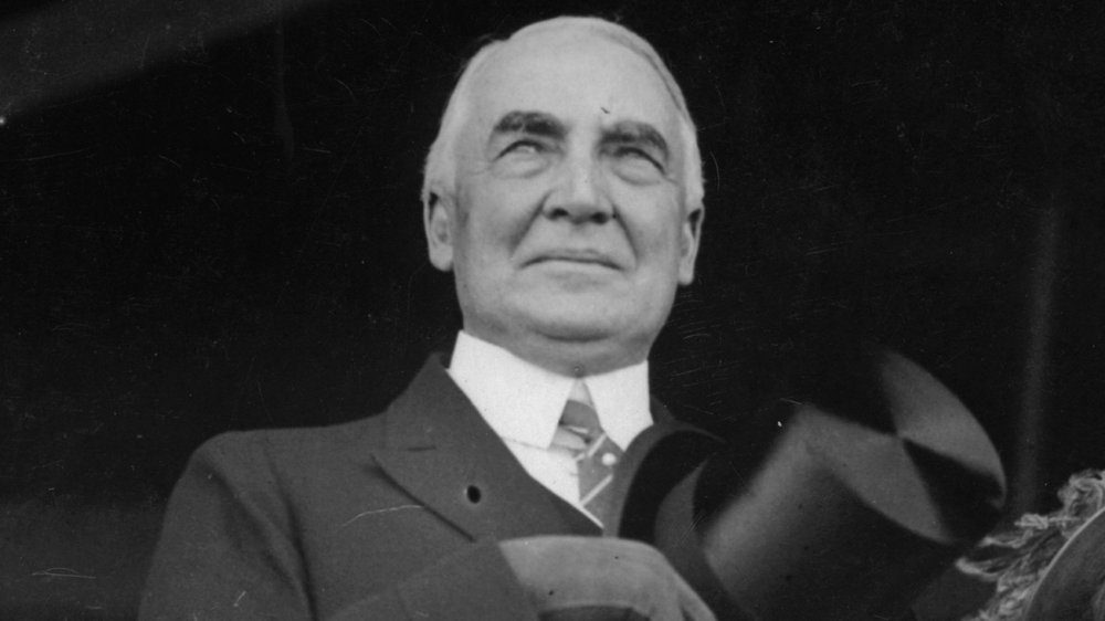 Warren Harding holding his hat and gazing off-camera