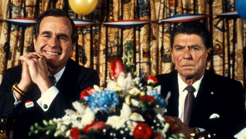 George H.W. Bush and Ronald Reagan seated with flowers in front of them