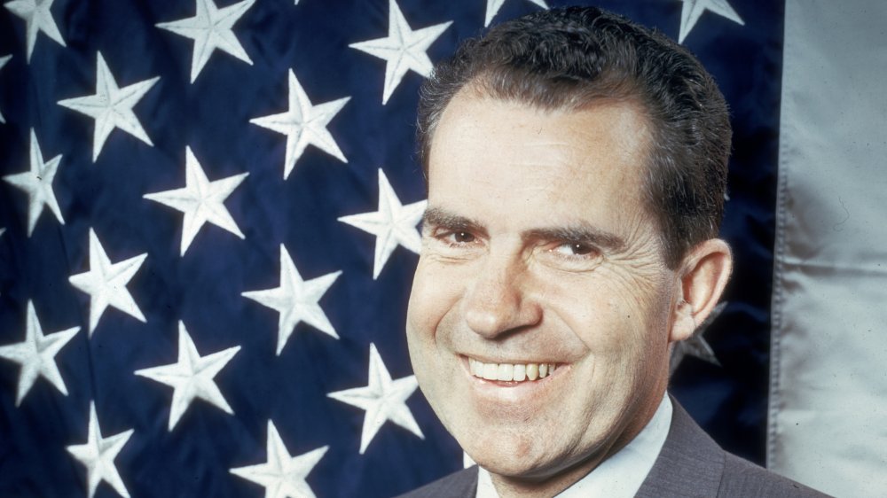 Richard Nixon smiling in front of US flag