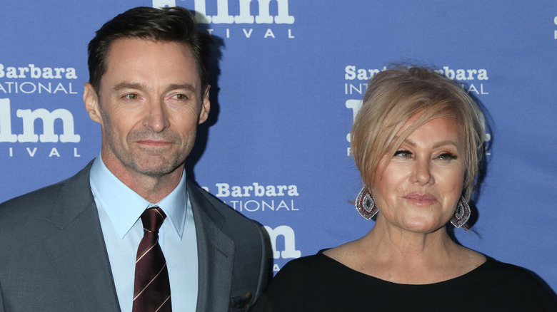 Hugh Jackman wearing a grey suit with Deborra-lee Furness wearing a black dress