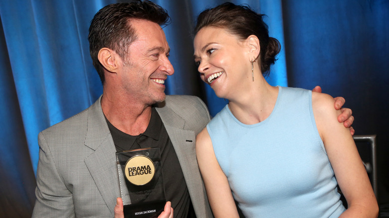 Hugh Jackman wearing a grey jacket with his arm around Sutton Foster wearing a powder blue strapless dress