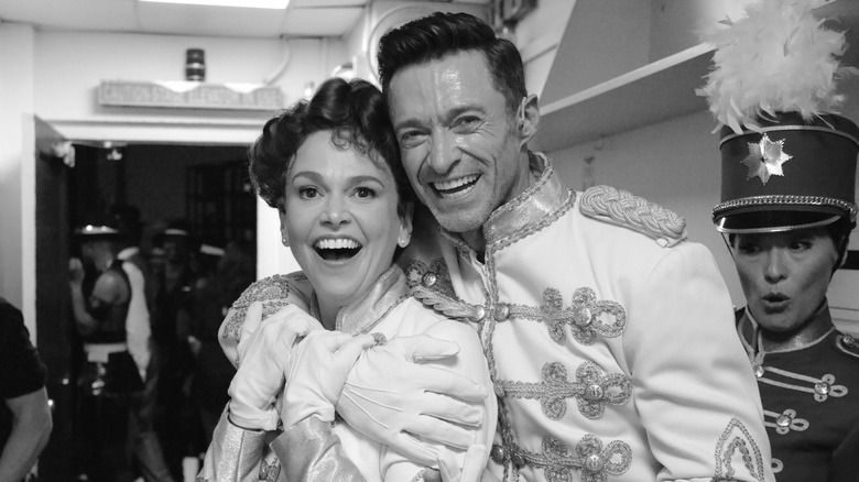 Sutton Foster and Hugh Jackman smiling backstage in white and gold band uniforms