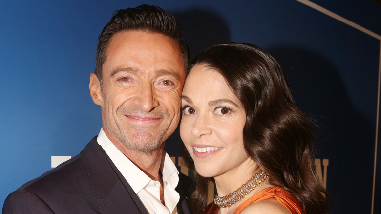 Hugh Jackman wearing a black suit and Sutton Foster wearing an orange gown