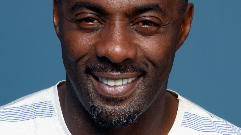 Idris Elba smiling in striped shirt