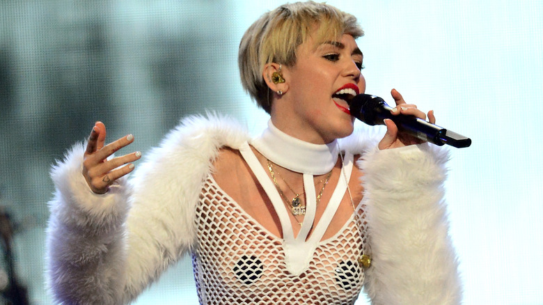 Miley Cyrus singing on stage in white mesh outfit