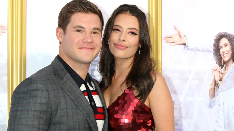 Adam Devine and Chloe Bridges posing at a premiere