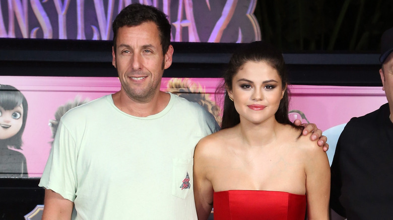 Adam Sandler posing with his arm around Selena Gomez