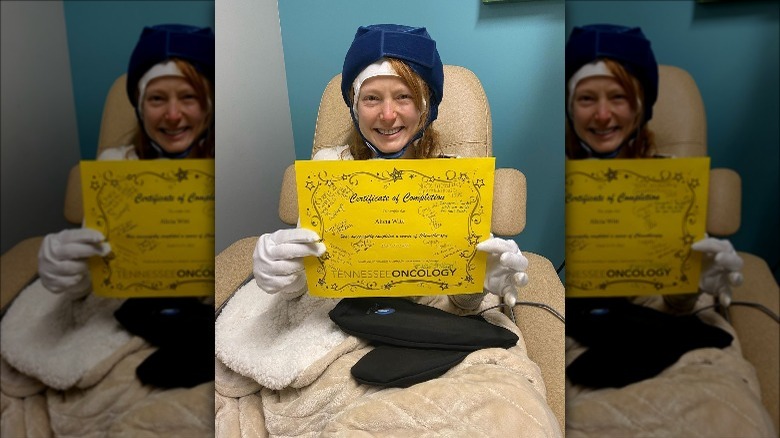 Alicia Witt smiles holding a certificate from Tennessee Oncology