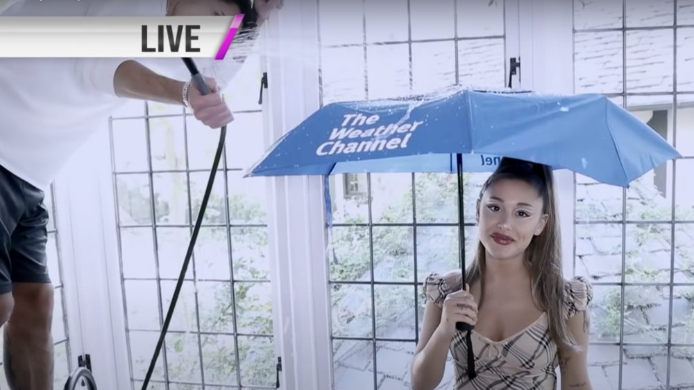 Dalton Gomez holding a showerhead above Ariana Grande with an umbrella