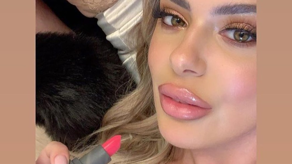 Brielle Biermann holding a lipstick from her makeup line