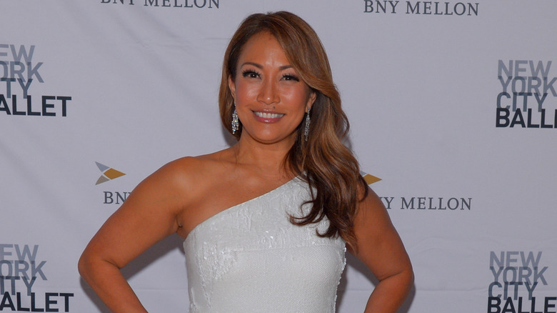 Carrie Ann Inaba with wide smile wearing one shoulder white top
