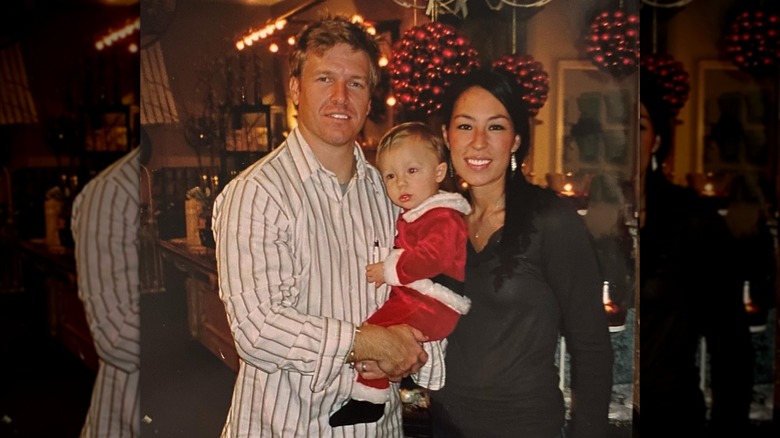 Chip Gaines holding his son Drake beside Joanna Gaines inside Magnolia Market