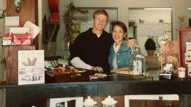 Chip Gaines with arm around Joanna Gaines behind Magnolia Market counter